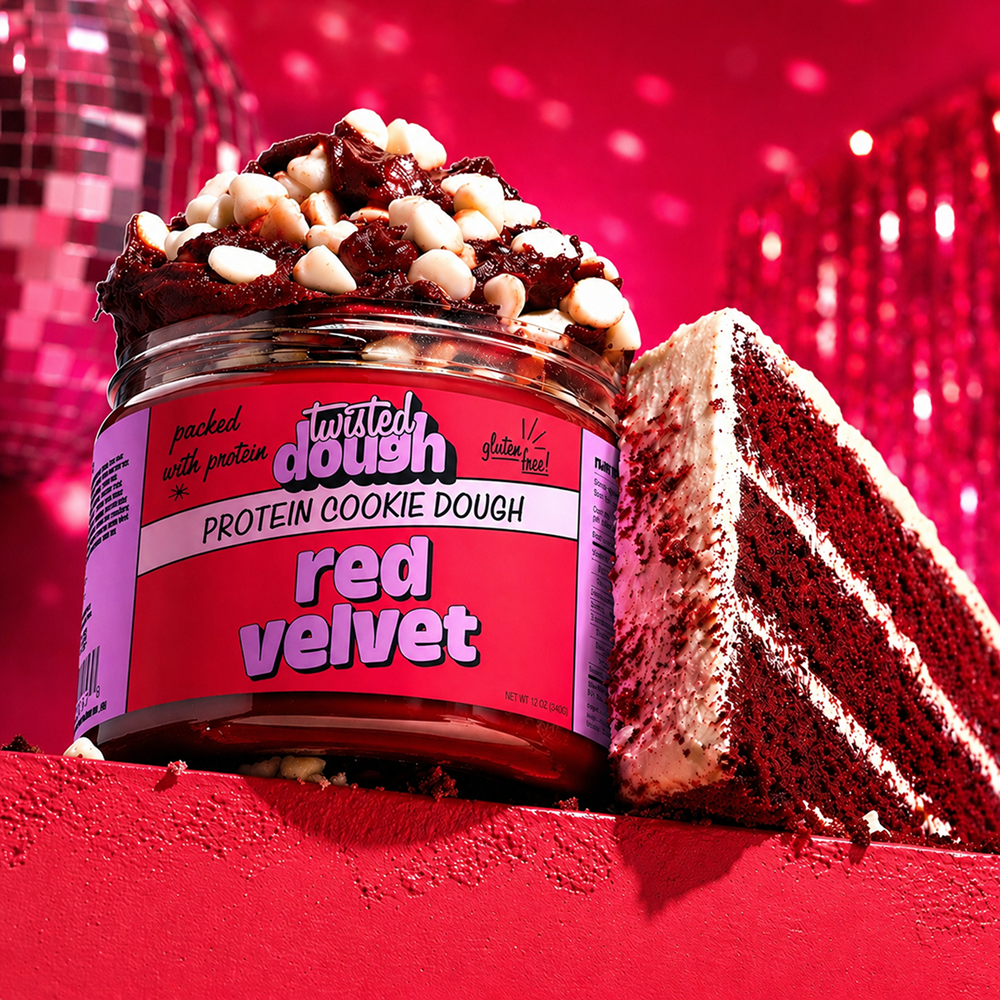 Jar of Twisted Dough Red Velvet Protein Cookie Dough with a slice of red velvet cake on a red background